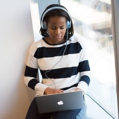 Girl sitting at her laptop, wearing headphones and working.